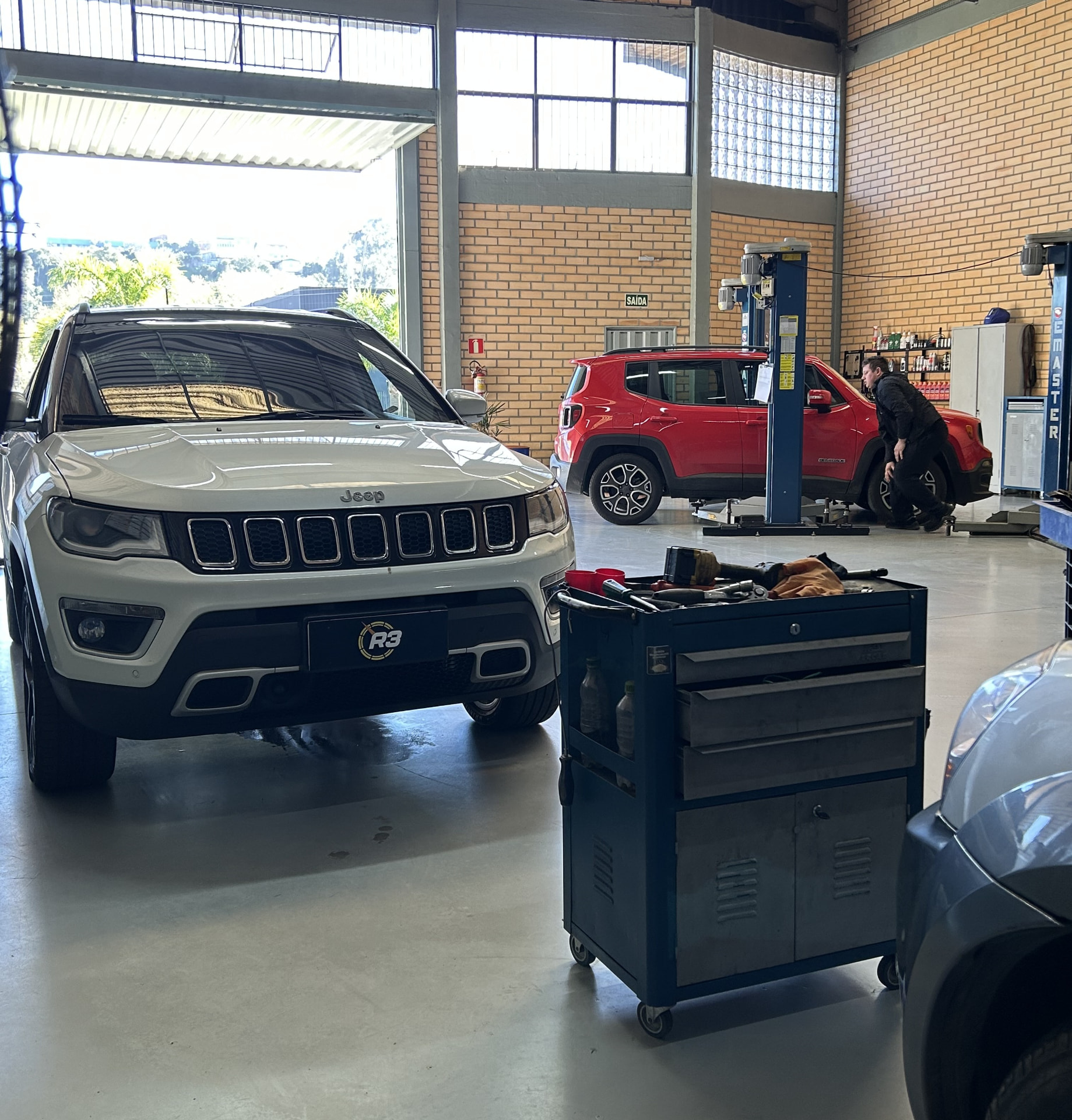 Jeeps na oficina da R3, com um Compass na frente e um Renegade vermelho no elevador